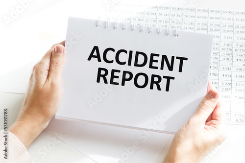 Accident report text on a notebook in the hands of a businessman on the background of an office desk