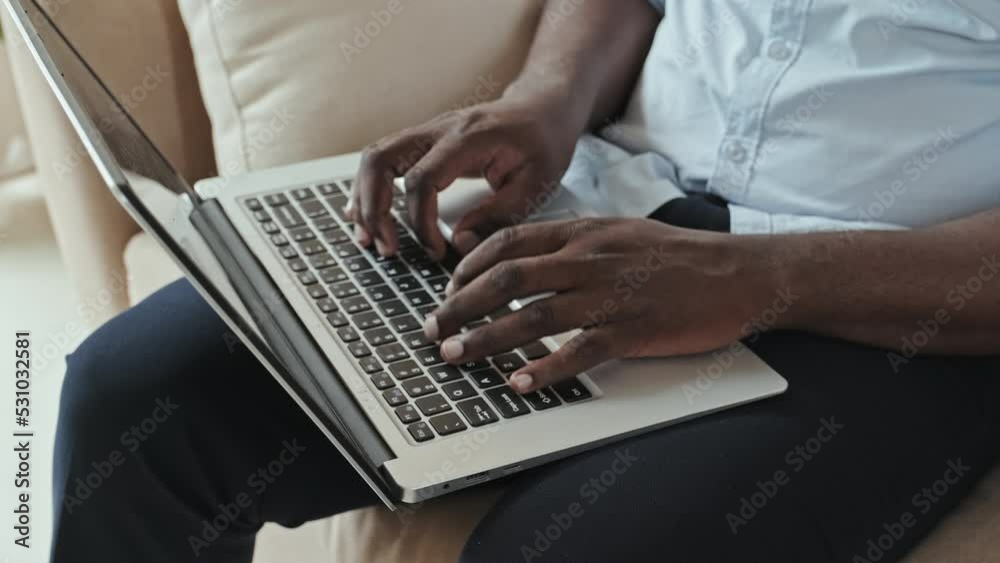 Hands of unrecognizable Black man typing on laptop. Work from home concept