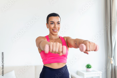 Domestic Training With Weights. Positive black lady doing exercises with dumbbells, strengthening her body at home. Smiling young female working on her biceps muscles, staying healthy