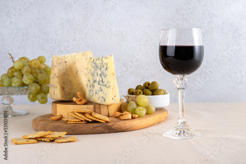 Glass of red wine with grapes and cheese on light table background. Red wine with cheese and fruits. Space for text