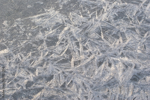 Ice crystals in a frozen puddle. Wallpaper with ice crystals texture.