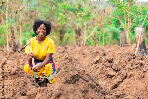 female african farmer squatting and smiling