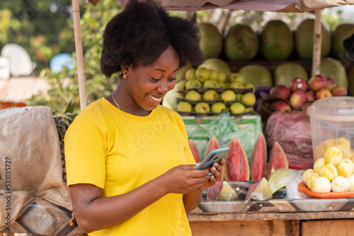 african market woman using her phone to text