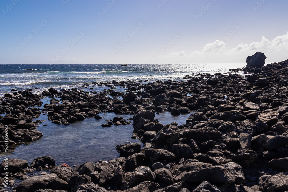 Scenic view on the pebble beach Playa de Vueltas in Valle Gran Rey, La Gomera, Canary Islands, Spain, Europe. Calm atmosphere at the seaside. Incoming waves hitting the shoreline. Surfing vibes Scenic view on the pebble beach Playa de Vueltas in Valle Gran Rey, La Gomera, Canary Islands, Spain, Europe. Calm atmosphere at the seaside. Incoming waves hitting the shoreline. Surfing vibes