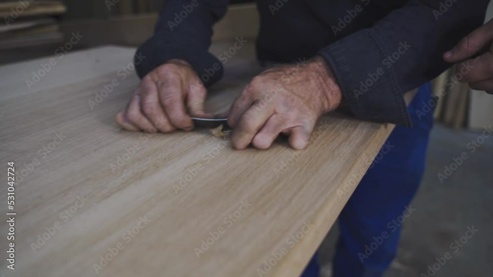 a carpenter apprentice raking wood with a scraper a carpenter apprentice raking wood with a scraper
