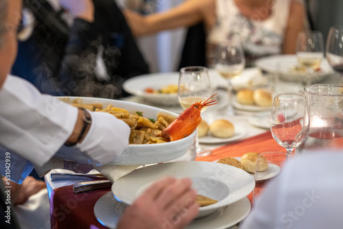 Cerimonia, servire a tavola, cameriere che serve pietanza a base di pesce tra commensali photo