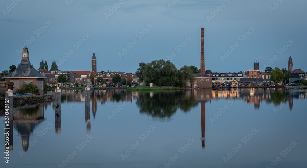 Dutch village Halfweg, which is part of the municipality of Haarlemmermeer, with the Ringvaart canal in the foreground at dusk