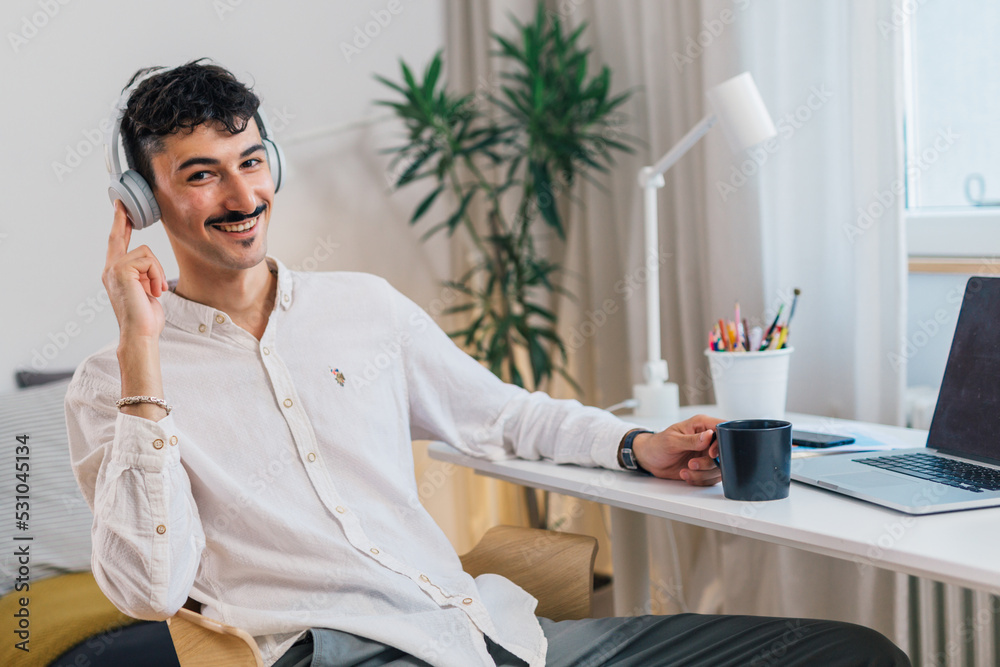 college male student sits in his room and listening music on head phones