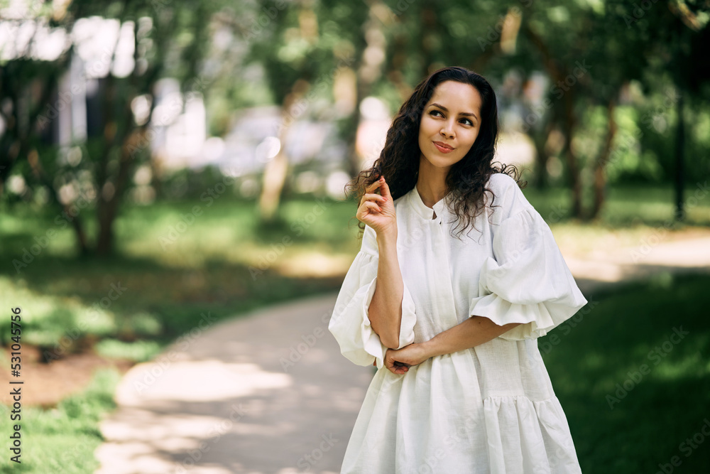 Curly-haired brunette girl in the park. Girl thinking and holding her hair. High quality photo Curly-haired brunette girl in the park. Girl thinking and holding her hair. High quality photo