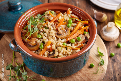 Fotografi Pearl barley grain porridge with carrot, mushrooms, green peas and onion