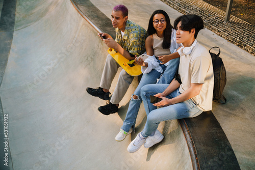 Three young smiling happy friends with phones sitting together