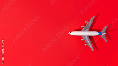 Top view of white model plane, airplane toy on isolated red background. Flat lay with copy space. Trip or travel banner..