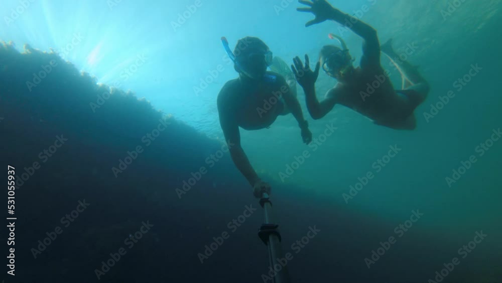 Male friends go snorkeling underwater on a sunny day. First person view from the action camera. Dive freediving
