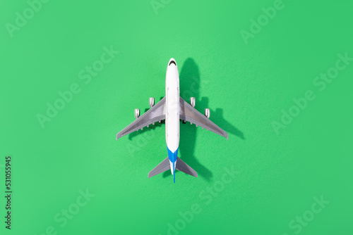 Top view of white model plane, airplane toy on isolated green background. Flat lay with copy space. Trip or travel banner..
