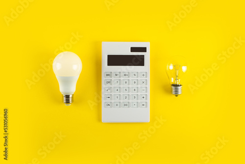 Fotobehang White calculator and incandescent lamp or LED bulb on yellow background