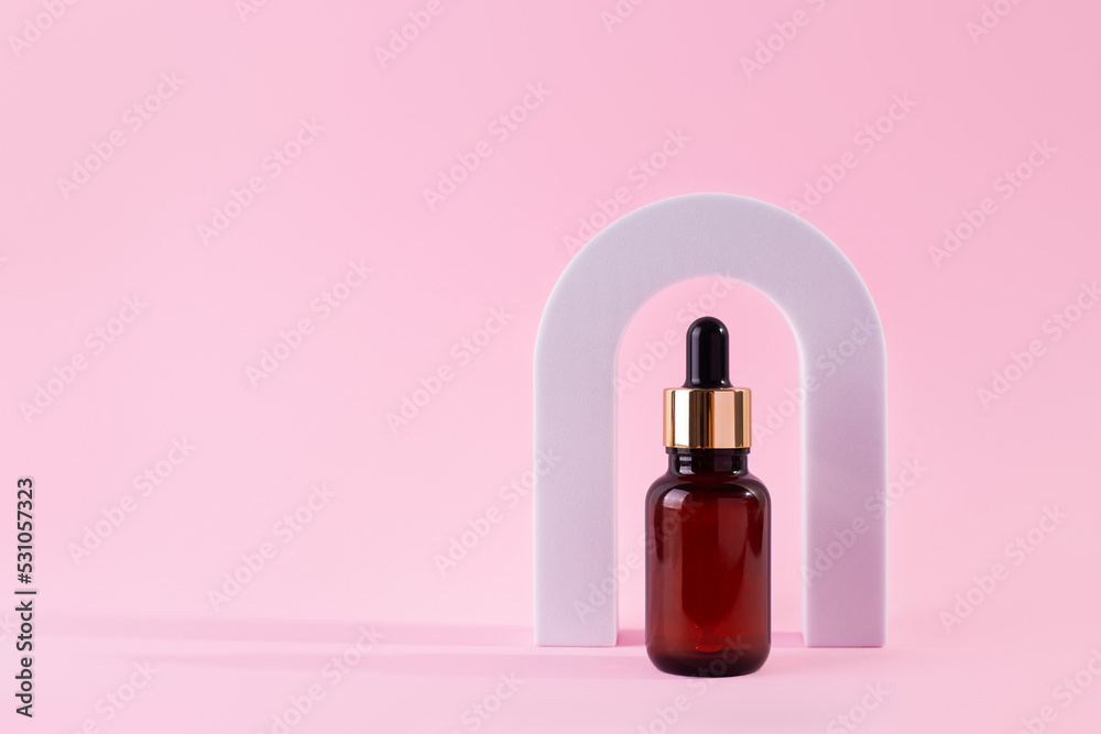 Beauty collagen face serum in a glass dropper bottle in Arch on pink background. Trendy shoot of cosmetics packaging. Essential oil with natural ingredients.. Beauty collagen face serum in a glass dropper bottle in Arch on pink background. Trendy shoot of cosmetics packaging. Essential oil with natural ingredients..