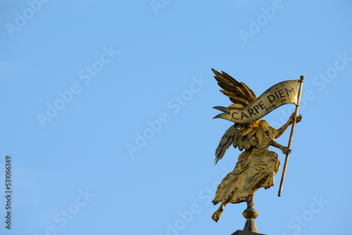 Golden angel carries a banner with the inscription: carpe diem photo