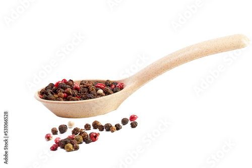 Mixture of peppers in a wooden spoon and scattered balls of pepper on a white background, seasonings, spices, kitchen