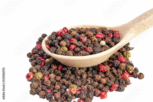 Pepper mixture in wooden spoon on a slide of pepper mixture close-up on white background, seasonings, spices, kitchen. Floating Focus