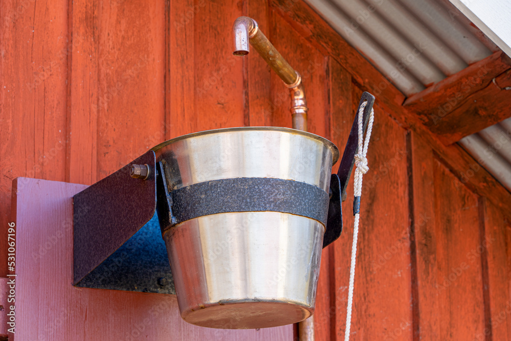 Wooden bucket on a rope with cold water in sauna, finish, cold shower of pails