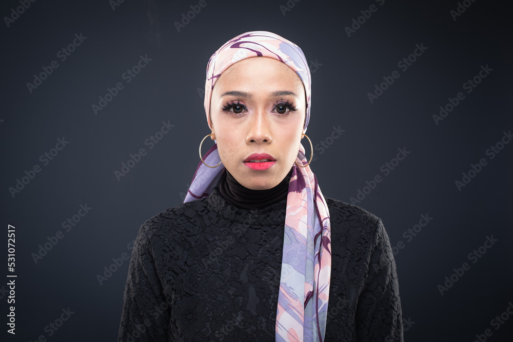 Portrait of a beautiful female model wearing hijab, a lifestyle apparel for Muslim women isolated on grey background. Idul Fitri and hijab fashion concept. Portrait of a beautiful female model wearing hijab, a lifestyle apparel for Muslim women isolated on grey background. Idul Fitri and hijab fashion concept.