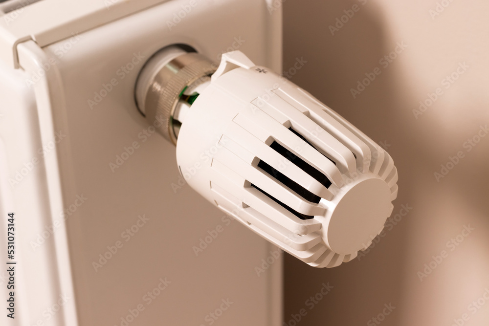Control valve of home heating radiator in modern living room. Temperature regulator. Low temperature reduces heating costs Control valve of home heating radiator in modern living room. Temperature regulator. Low temperature reduces heating costs