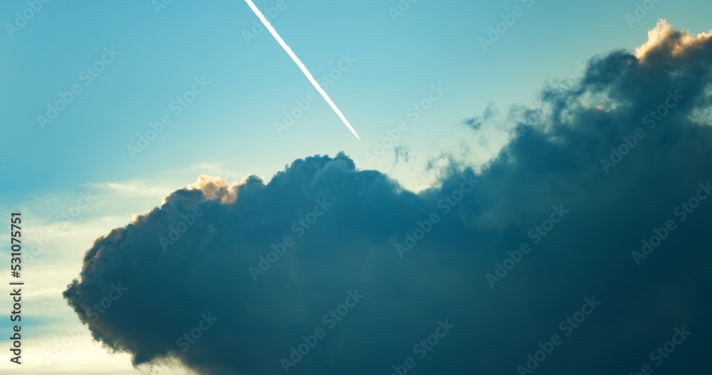 Large cloud against blue sky with airplane