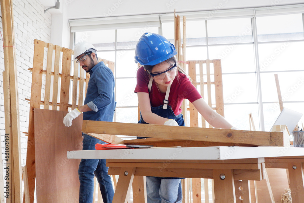 A female carpenter uses a tape measure to measure the distance to the wooden planks. inside the carpentry shop carpentry concept.