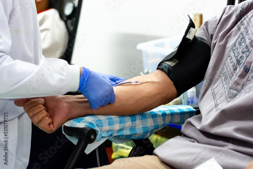 Doctor helps patient donate blood. the doctor's hand puts a needle into the blood donor's arm