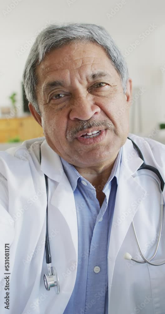 Vertical video of friendly senior biracial male doctor talking during video call Vertical video of friendly senior biracial male doctor talking during video call