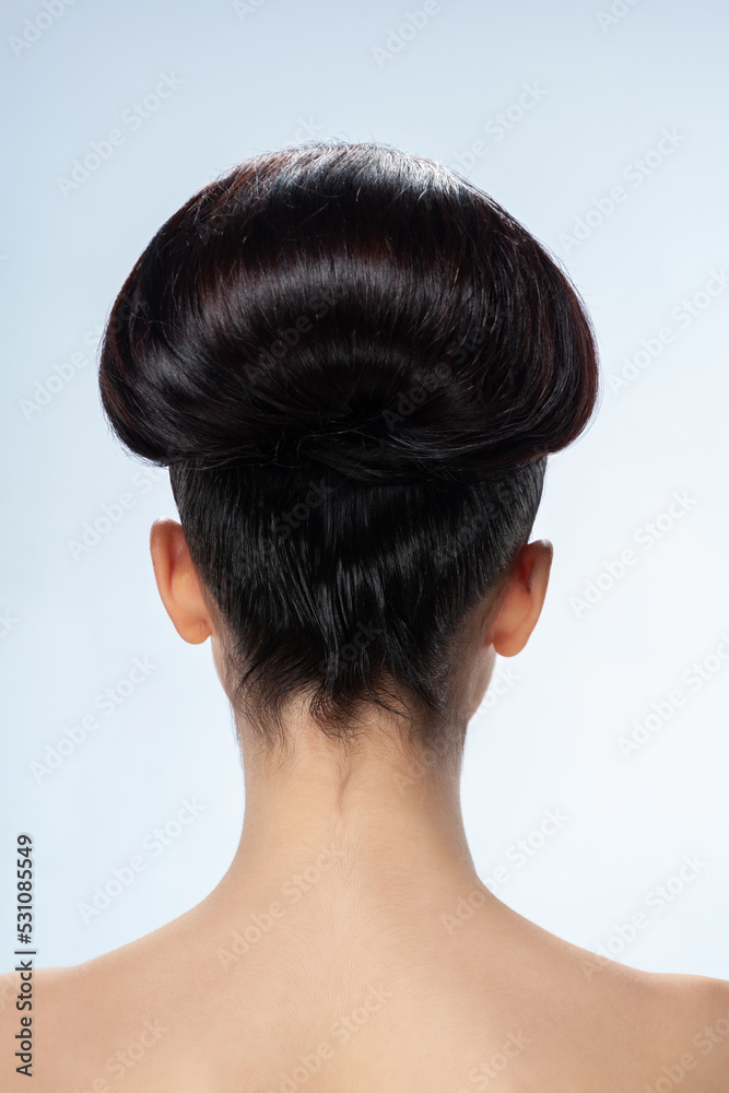 Back view of young woman with smooth hair. Portrait of a naked young white woman. Dark hair. Stylish hairstyle. Isolated on a light