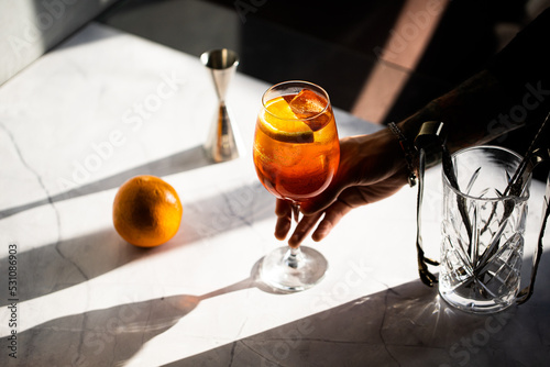 Canvastavla photography of a man's hand holding aperol spritz cocktail glass with orange sli