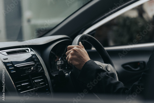 A man in a suit is driving a car to work, he is driving a car to work at the company. Vehicle driving concept. © kamiphotos