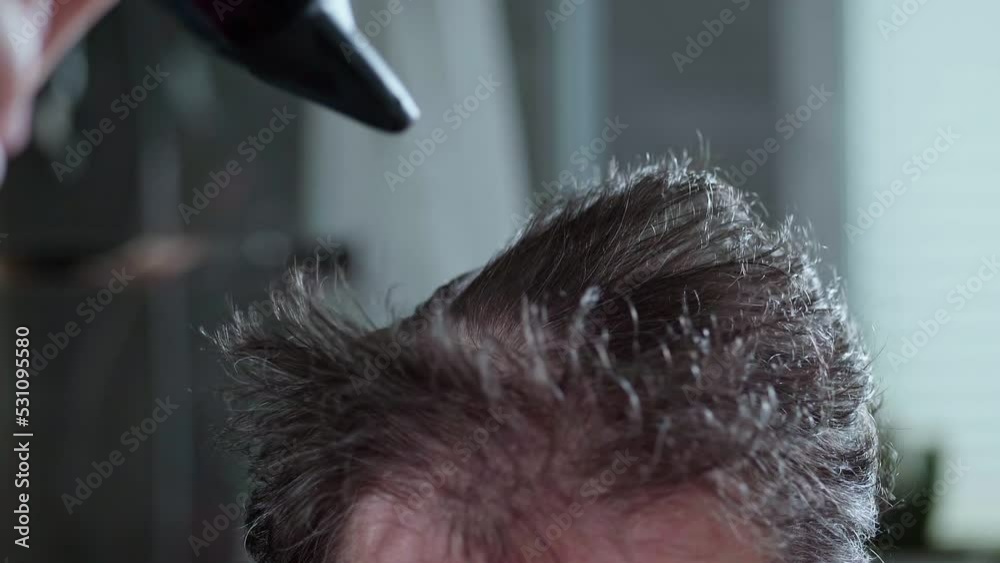 The man is drying his crazy hair, thinning hair. Slow motion video. The man is drying his crazy hair, thinning hair. Slow motion video.