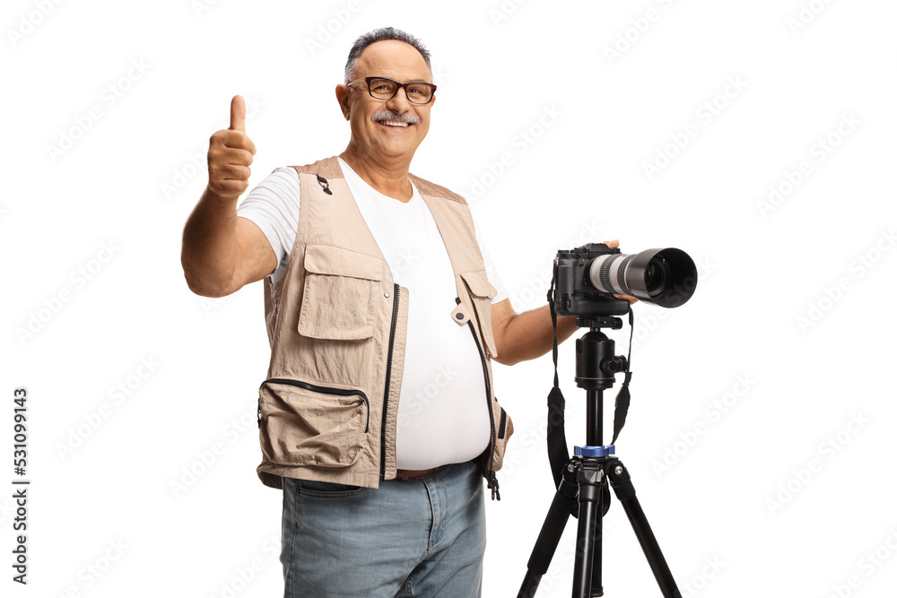 Mature male photographer with a camera on a stand gesturing thumbs up ...