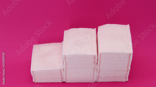 Almoadillas de algodon absorvente apiladas sobre un fondo rosa. photo