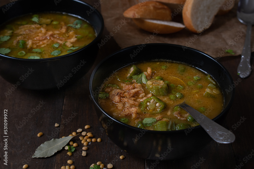 Vegan lentil, okra and peas soup, topped with crispy onions, served in black bowls