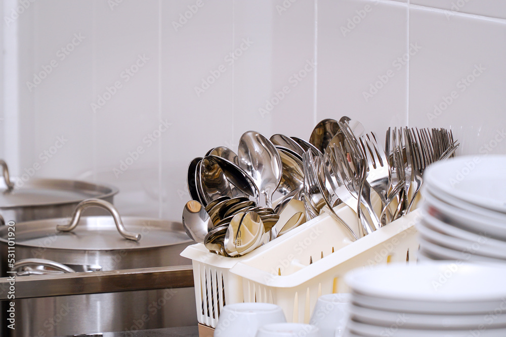 Clean spoons and forks in a stand on the table StockFoto Adobe Stock