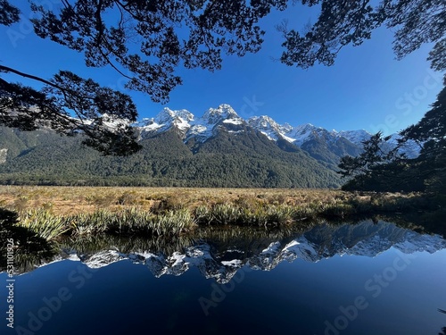 Beautiful landscape of snowy mountain range symmetrically reflecting on the lake water photo