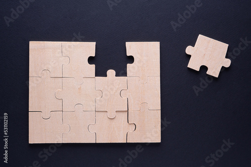 Business concept with wooden jigsaw puzzle on black background.