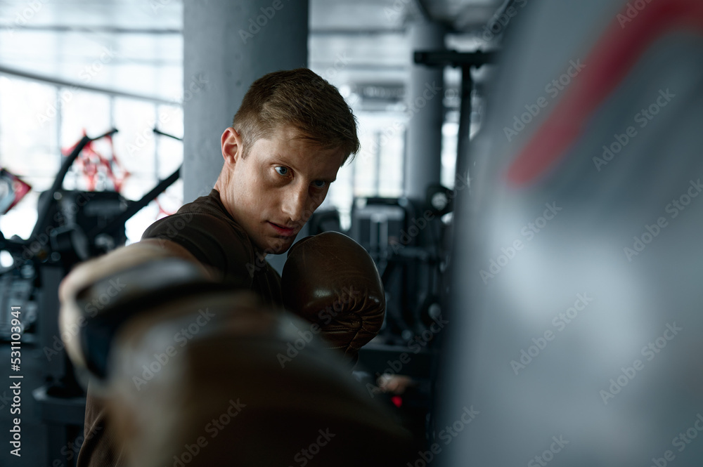 Closeup boxer trains with punching bag in gym Closeup boxer trains with punching bag in gym
