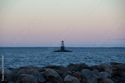 An automatic lighthouse outside a rocky coastline in Malmö Sweden during winter sunset