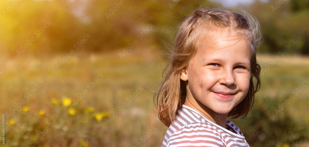 Smiling little girl in the park. Copy space. Happy child looking at the camera. Portrait of a laughing kid outside. Banner. Smiling little girl in the park. Copy space. Happy child looking at the camera. Portrait of a laughing kid outside. Banner.