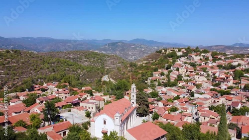 Aerial drone footage of traditional countryside village Lofou, in Limassol, Cyprus. Establish scene of christian church Panayia Chrysolofitissa, ceramic tiled roof houses and narrow streets from above