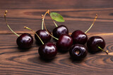 Sweet cherries with cherry leaf on a wooden background.