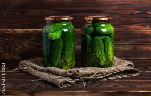 Preservations, conservation. Salted, pickled cucumbers in a jar on an old wooden table. Cucumbers, herbs, dill, garlic.
