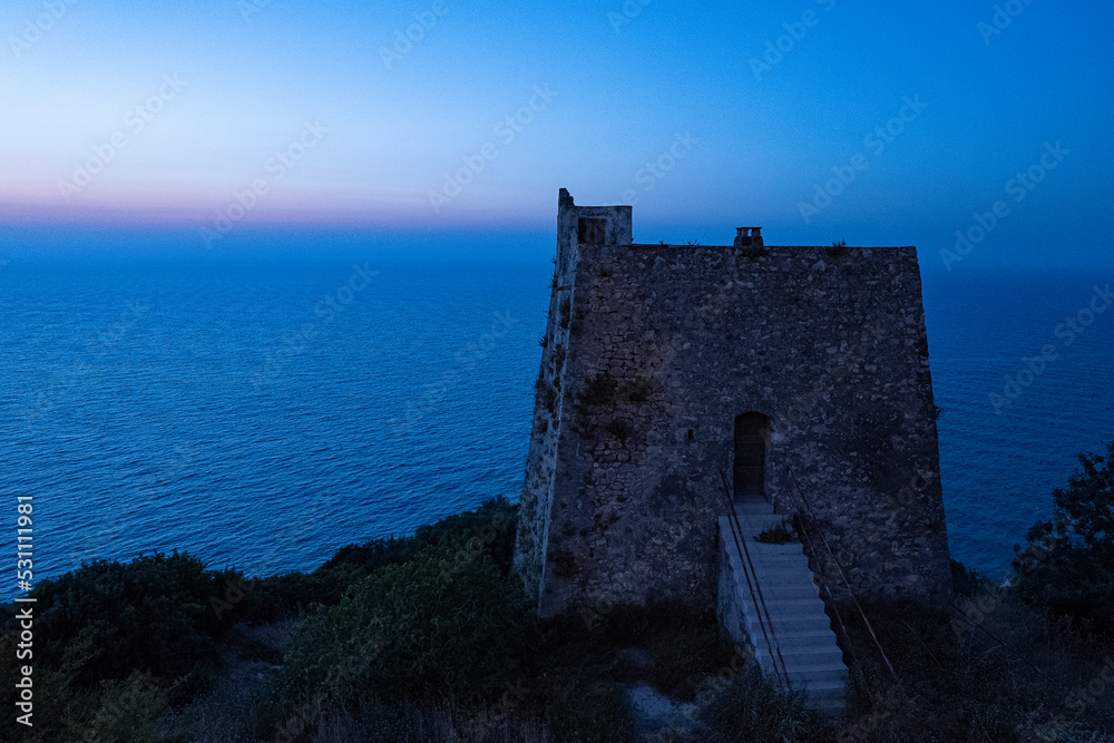 Peschici view of the medieval watchtower. silhouette of the tower on the blue sea.