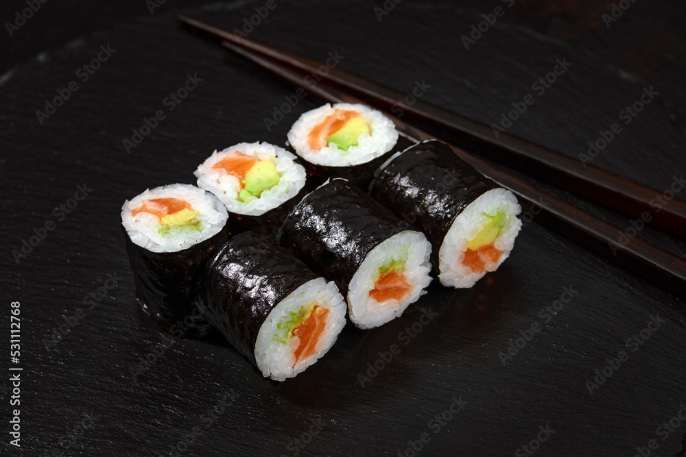 Set of tuna and avokado sushi rolls on black desk background Set of tuna and avokado sushi rolls on black desk background