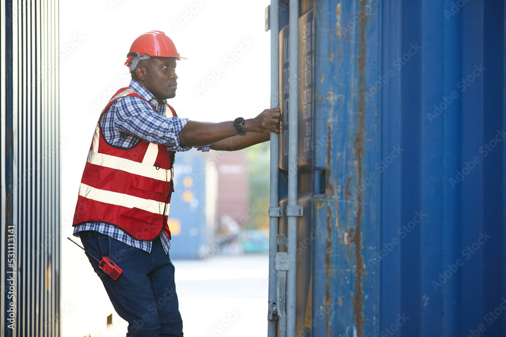 African factory worker or foreman opening the container door in warehouse storage African factory worker or foreman opening the container door in warehouse storage