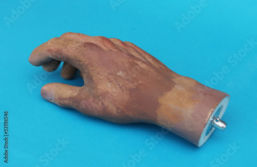 Wrist of man's plastic hand on blue background.
